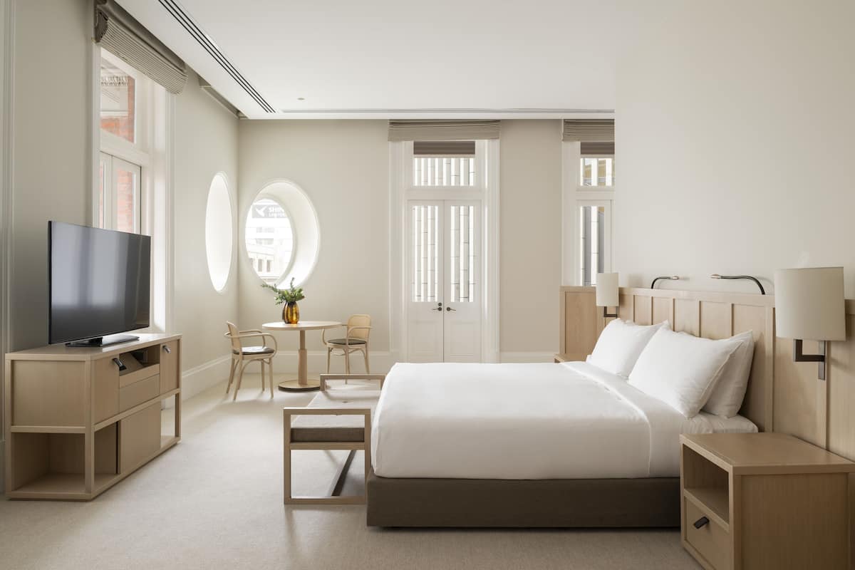 Ein Hotelzimmer mit Bett, Nachttischen, Fernseher, Schreibtisch und Stühlen.