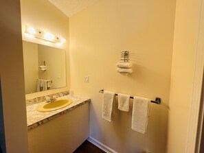 A bathroom with a marble sink, a mirror, and a towel rack with towels.