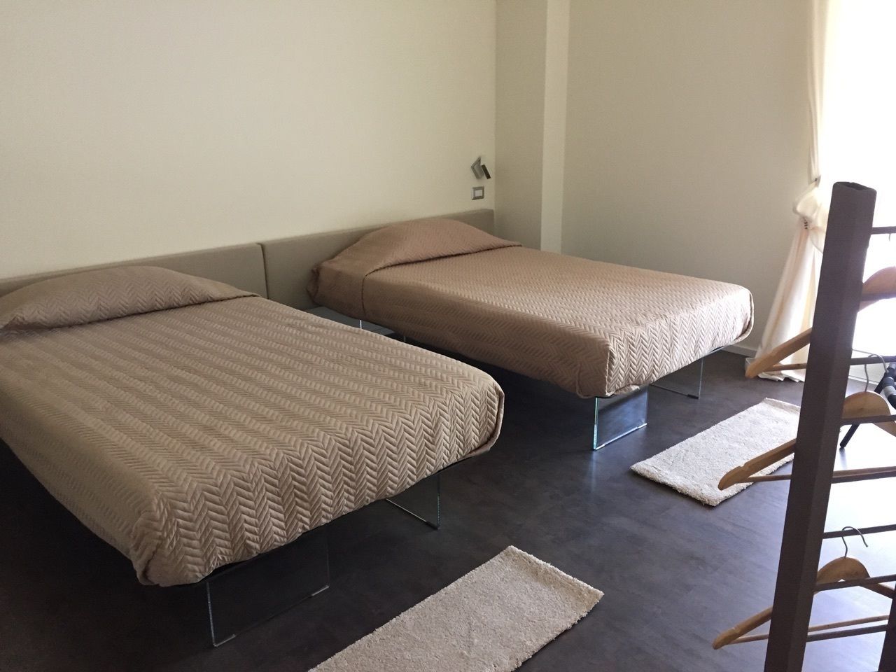 A room with two beds, a small rug, and a chair.