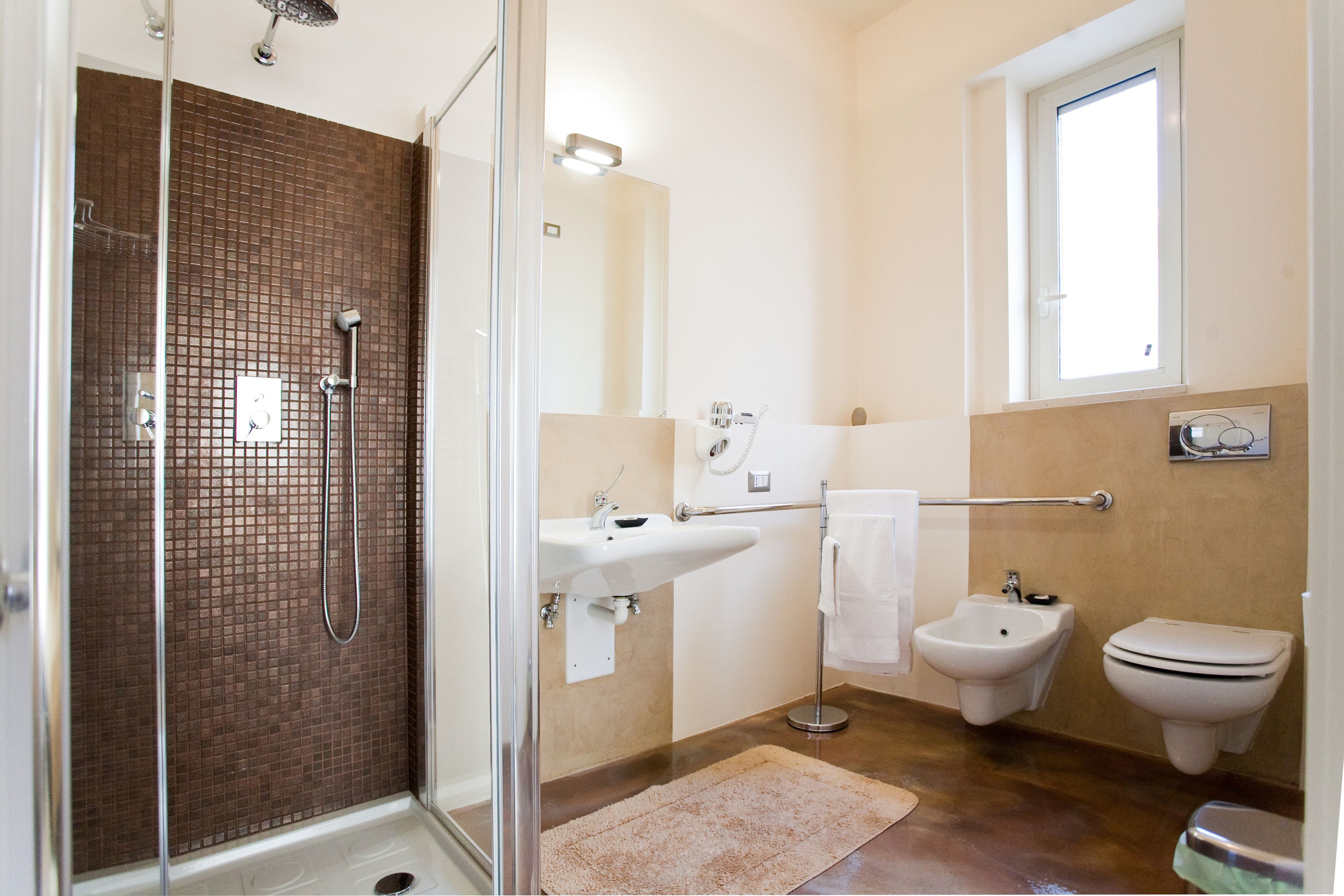 Une salle de bain avec une douche à parois de verre, un lavabo, un bidet et une fenêtre.