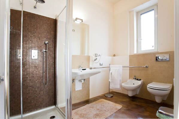 A bathroom with a glass shower enclosure, a sink, bidet, and a window. - Cinquecento B&B (Barcellona Pozzo di Gotto)