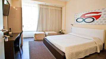A hotel room with a bed, a desk, a chair, a TV, a window with curtains, and a wall with a logo.