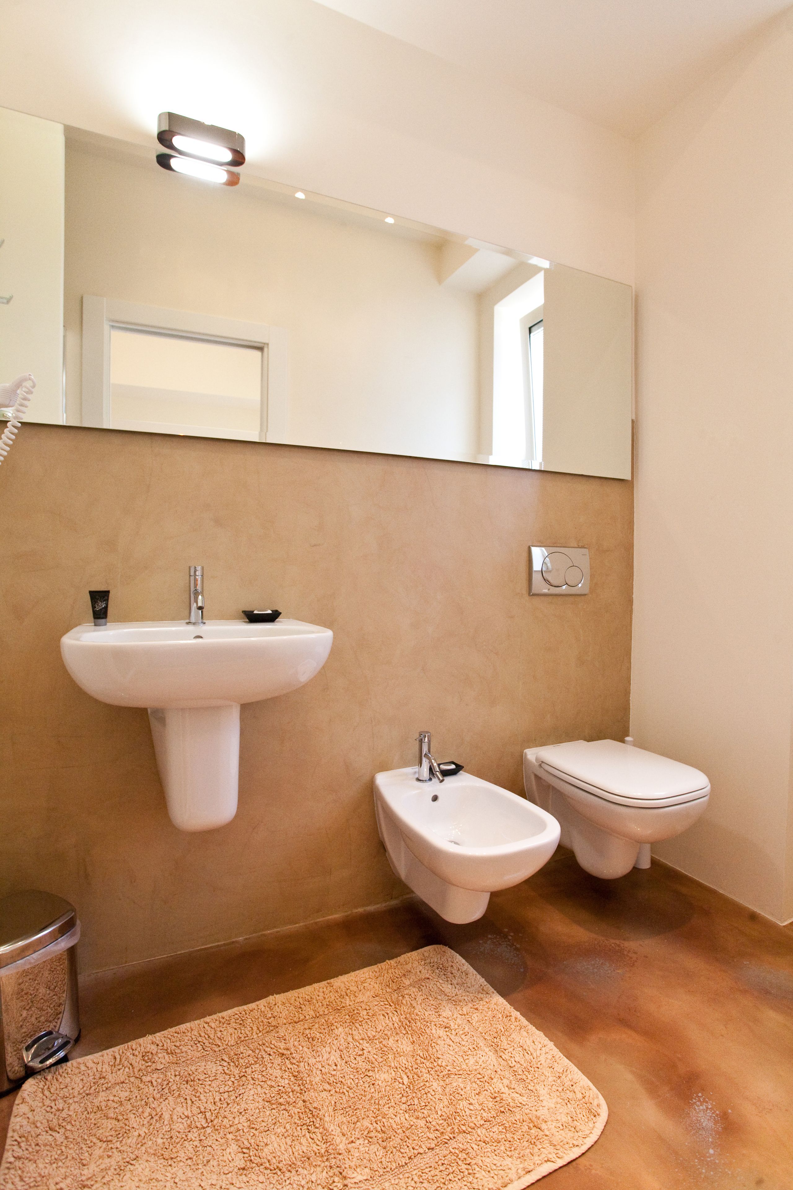 A bathroom with a sink, bidet, toilet, and a mirror.