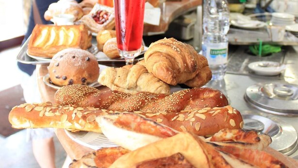 A breakfast buffet with various pastries and a tall glass of red beverage.