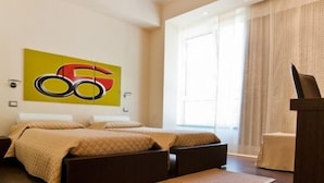 A modern bedroom with a large bed, a sofa bed, a large window with curtains, and a unique wall art piece.