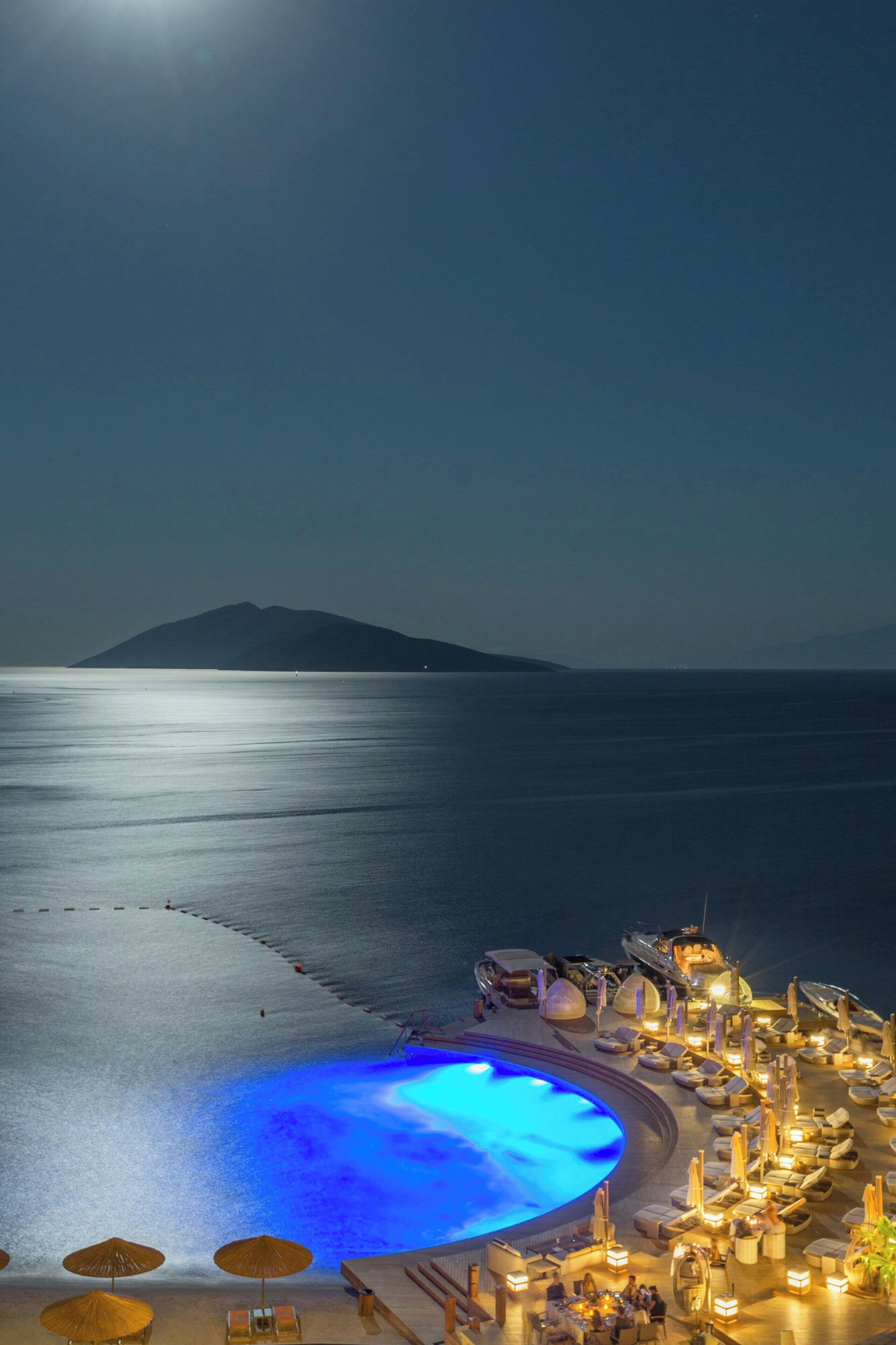 Un complexe hôtelier en bord de mer, doté d’une piscine, de chaises longues et de parasols.