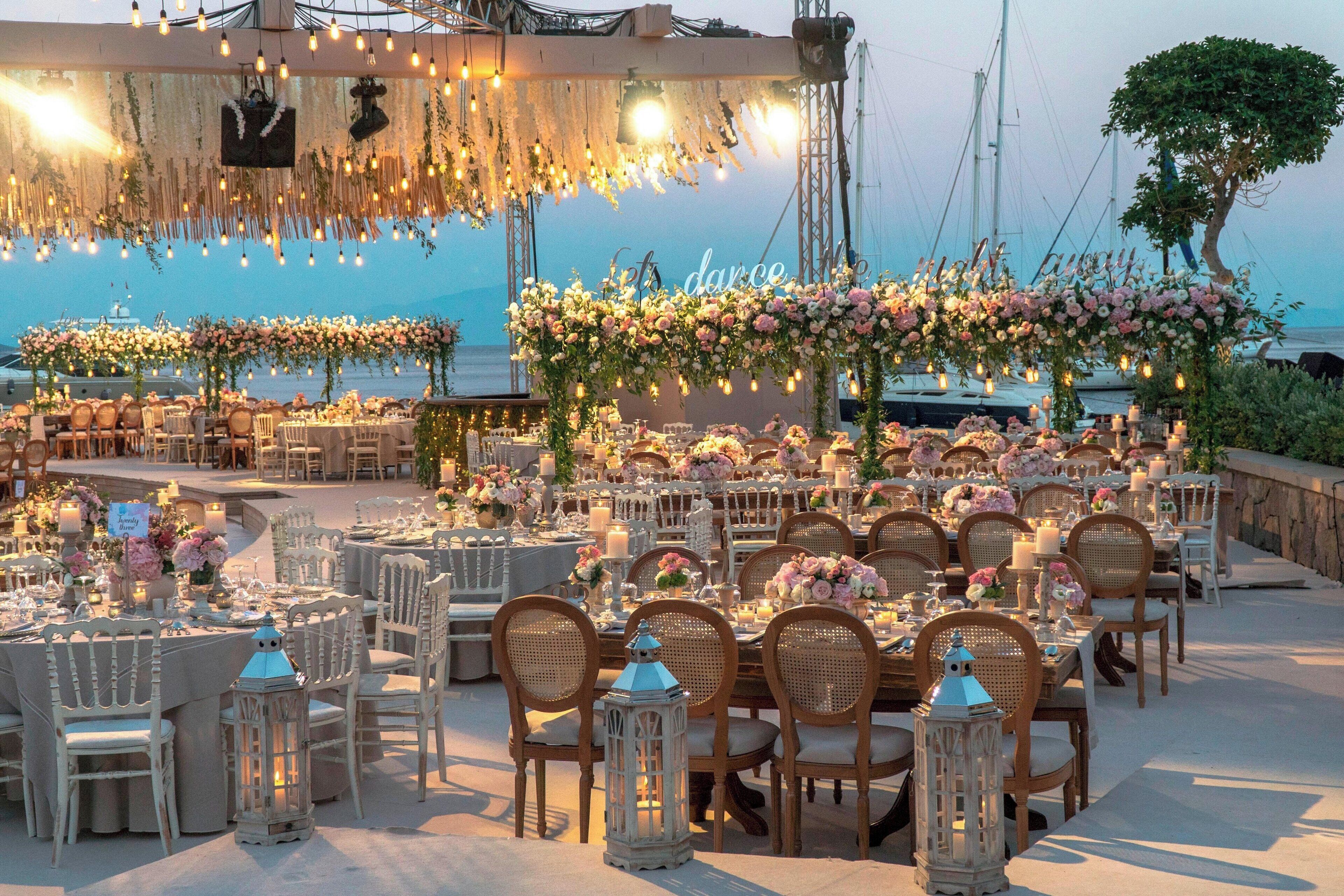 An outdoor dining area with round tables, wicker chairs, and lanterns.
