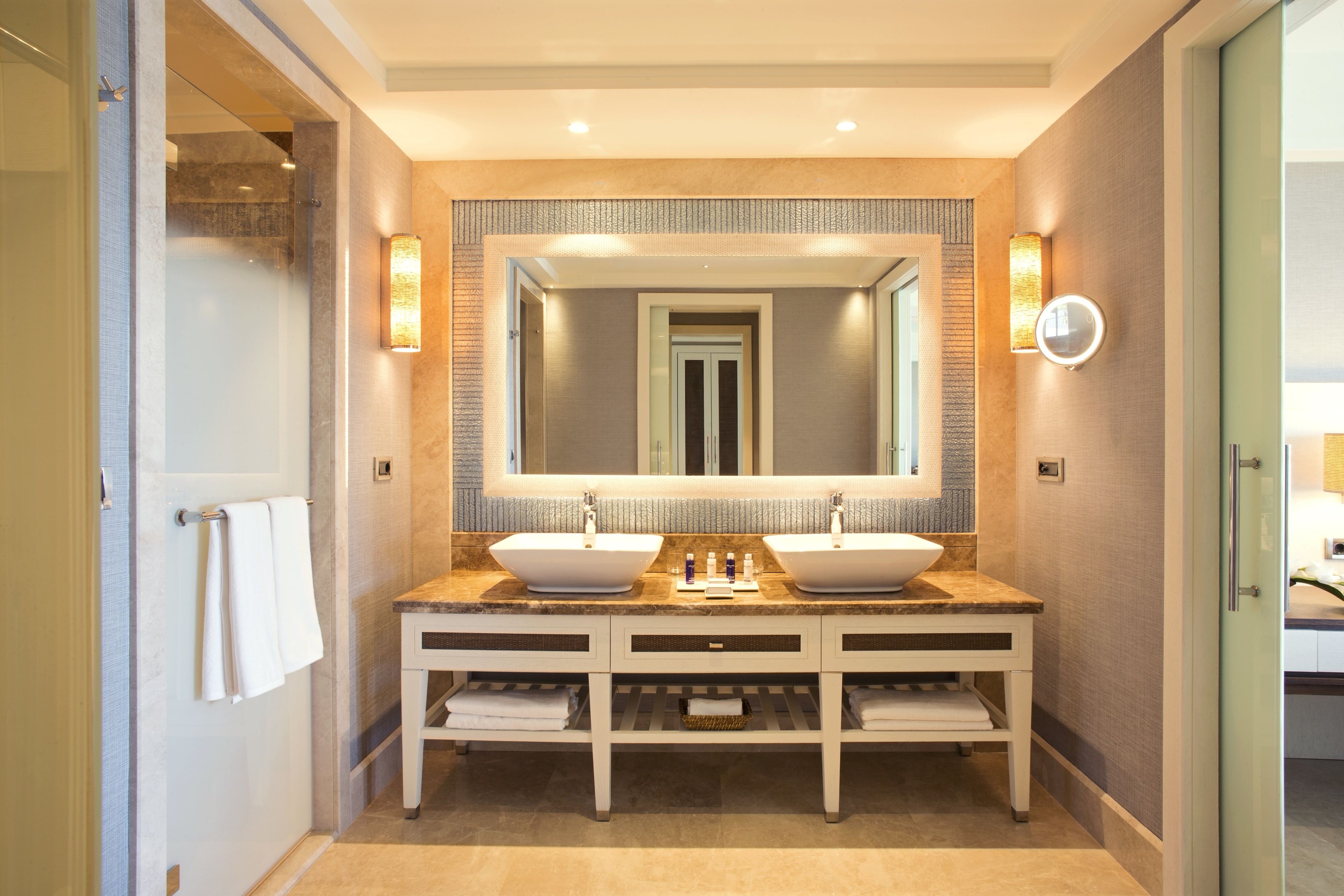 A modern bathroom with two sinks, a large mirror, and a towel rack.