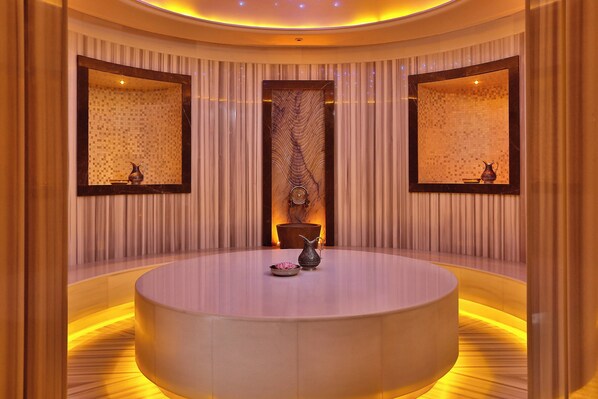 A circular seating area with a central table, flanked by two large mirrors and a patterned wall.