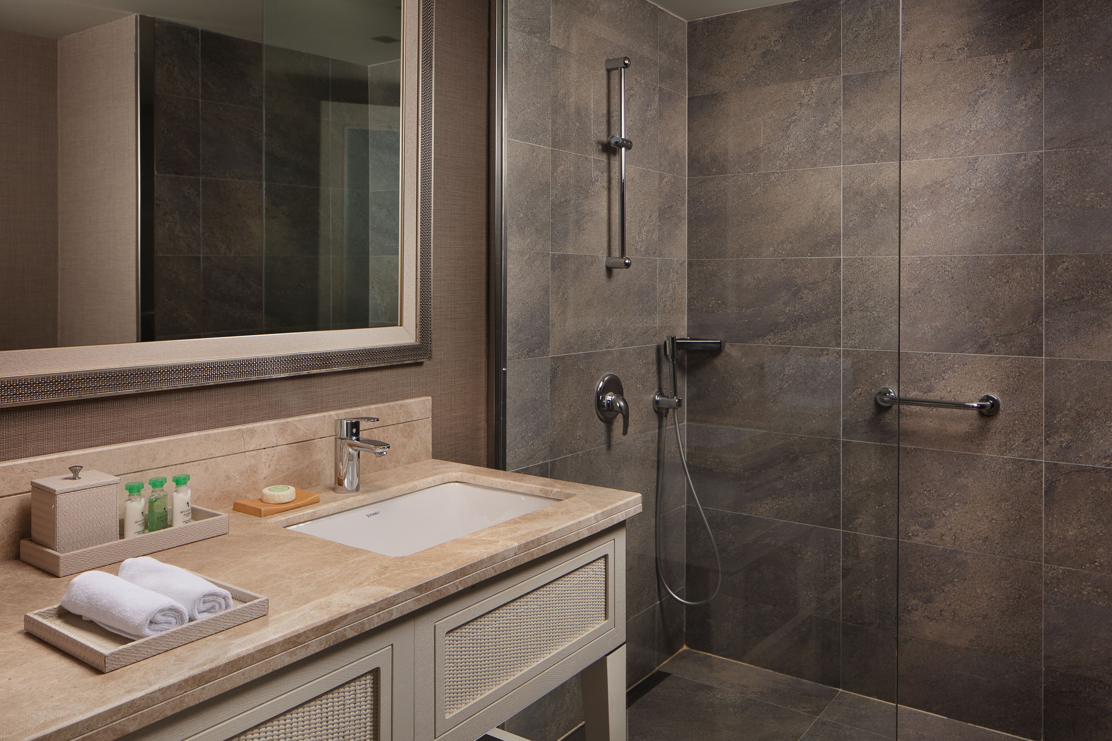 A modern bathroom with a large mirror, a sink, and a shower area.