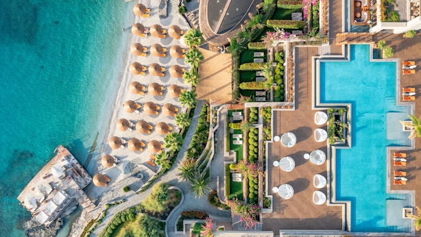 Vista aérea de un resort con una gran piscina, tumbonas y una zona de playa.