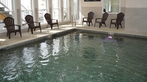 An indoor swimming pool with clear water, surrounded by wooden chairs and a television mounted on the wall. - Copley LaReine Motel (Old Orchard Beach)