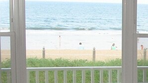 A view of a beach through a window with a wooden railing and a fence. - Copley LaReine Motel (Old Orchard Beach)