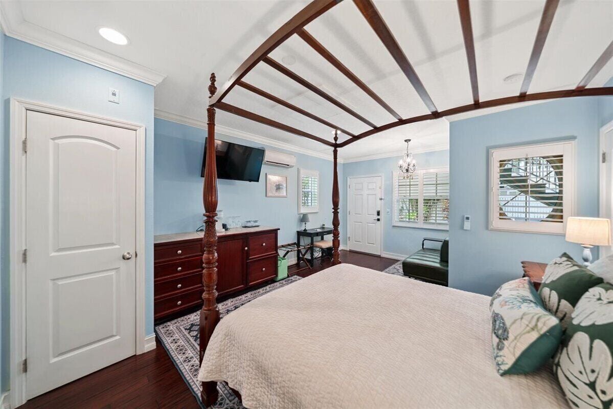 Une chambre à coucher avec un lit à baldaquin, une télévision, un bureau et une chaise.