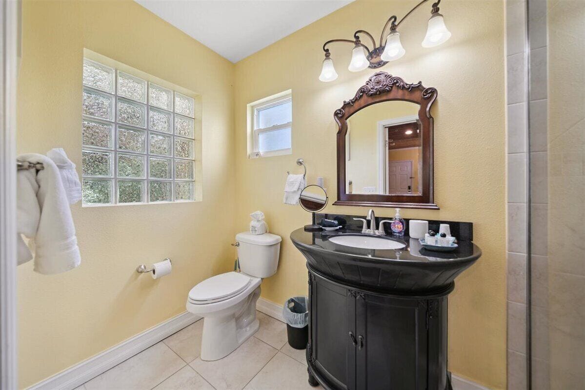 Een badkamer met toilet, wastafel, opbergmeubel en een grote spiegel.
