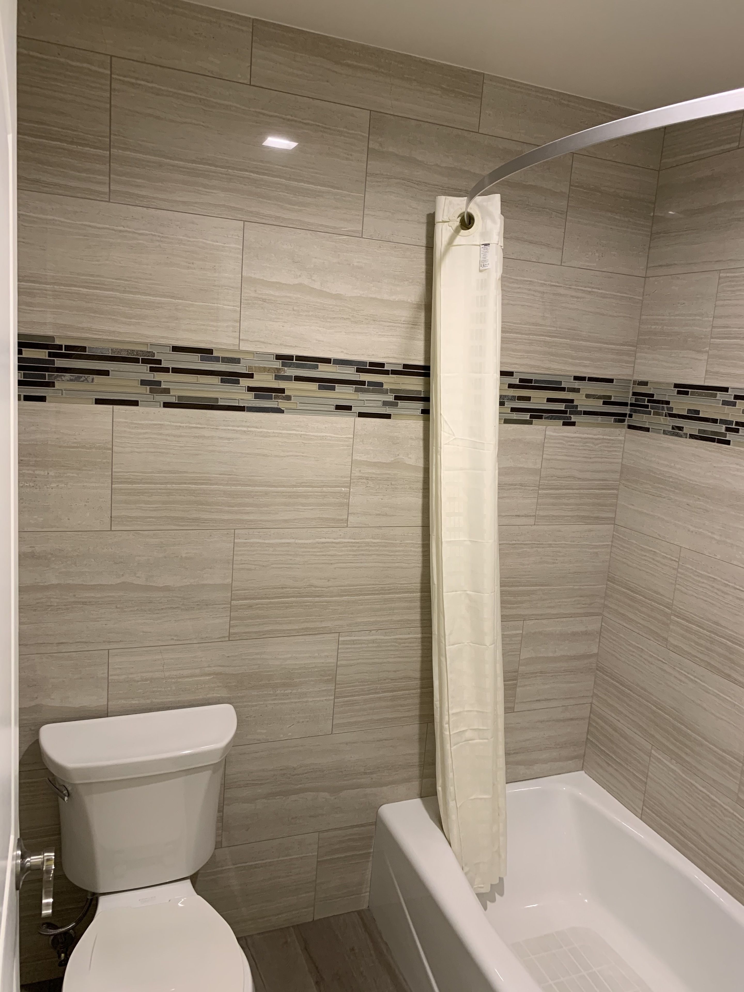 Un baño con inodoro, ducha con cortina y bañera.