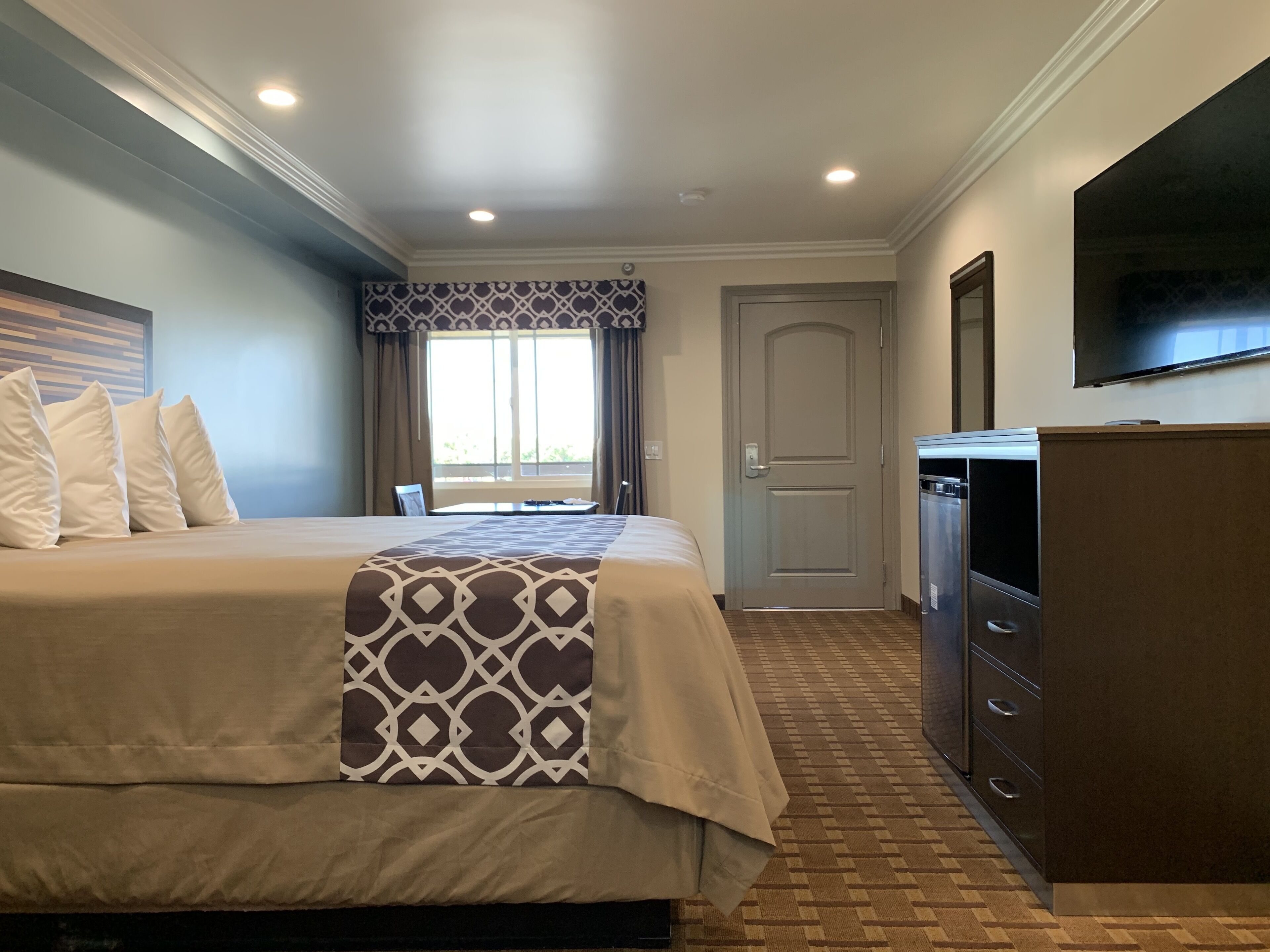 A hotel room with a bed, a desk, a television, and a wardrobe.