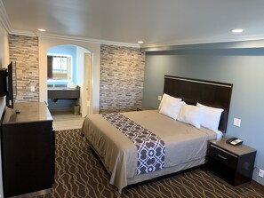 Ein Hotelzimmer mit Bett, Nachttisch und einem durch einen Bogen sichtbaren Badezimmer.