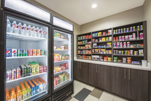 A refrigerated beverage cooler stocked with various drinks and a shelf stocked with snacks and food items.