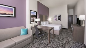 A hotel room with a bed, a desk, a chair, a sofa, and a TV. - La Quinta Inn & Suites by Wyndham Enid (Enid)