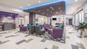 A modern lobby with seating areas, a reception desk, and a bar. - La Quinta Inn & Suites by Wyndham Enid (Enid)