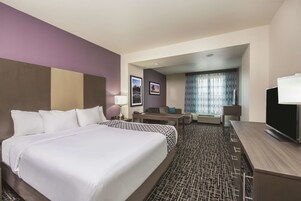 Habitación de hotel con una cama grande, un escritorio, un televisor y una zona de estar con vistas al exterior.