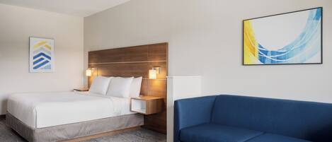 Ein Hotelzimmer mit einem Bett, einem blauen Sofa, einem Nachttisch aus Holz und einem Bild an der Wand.