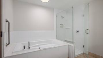 Un baño moderno con una bañera blanca, una cabina de ducha de vidrio y un pasamanos.