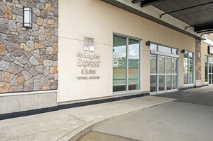 Un edificio con fachada de piedra, ventanas grandes y un cartel que dice 'Holiday Inn Express & Suites Victoria-Colwood'.