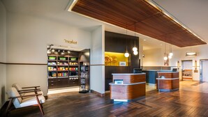 A reception area with a wooden floor, a reception desk, a seating area with a chair, and a store named "market" with shelves of products. - Courtyard by Marriott Calgary South (Calgary)