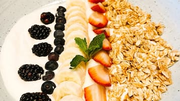 Un plato con rodajas de plátano, fresas, zarzamoras, arándanos y granola.