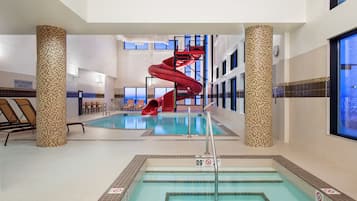 Ein überdachter Schwimmbereich mit roter Rutsche, Liegestühlen und einem Schild, das darauf hinweist, dass keine Badeaufsicht vorhanden ist.