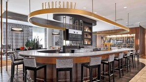 A modern bar area with a circular bar, multiple stools, and a sign reading "RENDESVOZ". - Courtyard by Marriott Calgary South (Calgary)