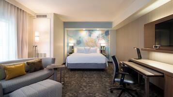 A hotel room with a bed, a desk, a sofa, and a TV.
