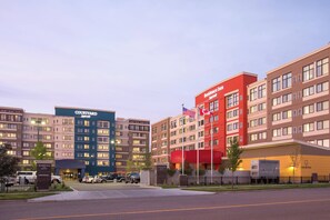 Un hotel Courtyard by Marriott con diseño moderno, con varios pisos y una destacada bandera estadounidense.