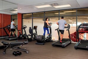 Un gimnasio con cintas de correr, elípticas y pesas libres.