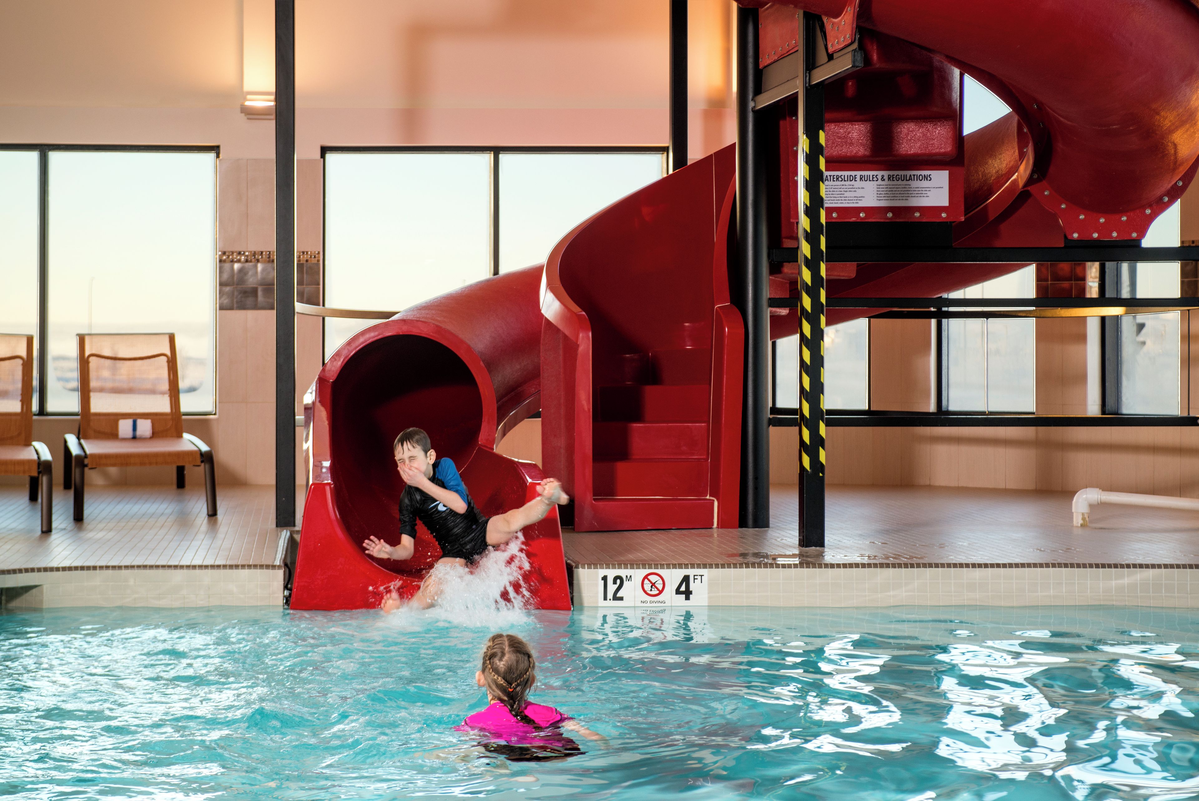 A pool area with a red water slide, a lifeguard stand, and a sign indicating no diving.
