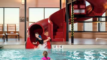 A pool area with a red water slide, a lifeguard stand, and a sign indicating no diving.