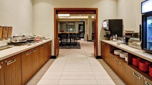 Een hotelkeuken met houten kastjes, een buffetopstelling en een televisie aan de rechterkant.