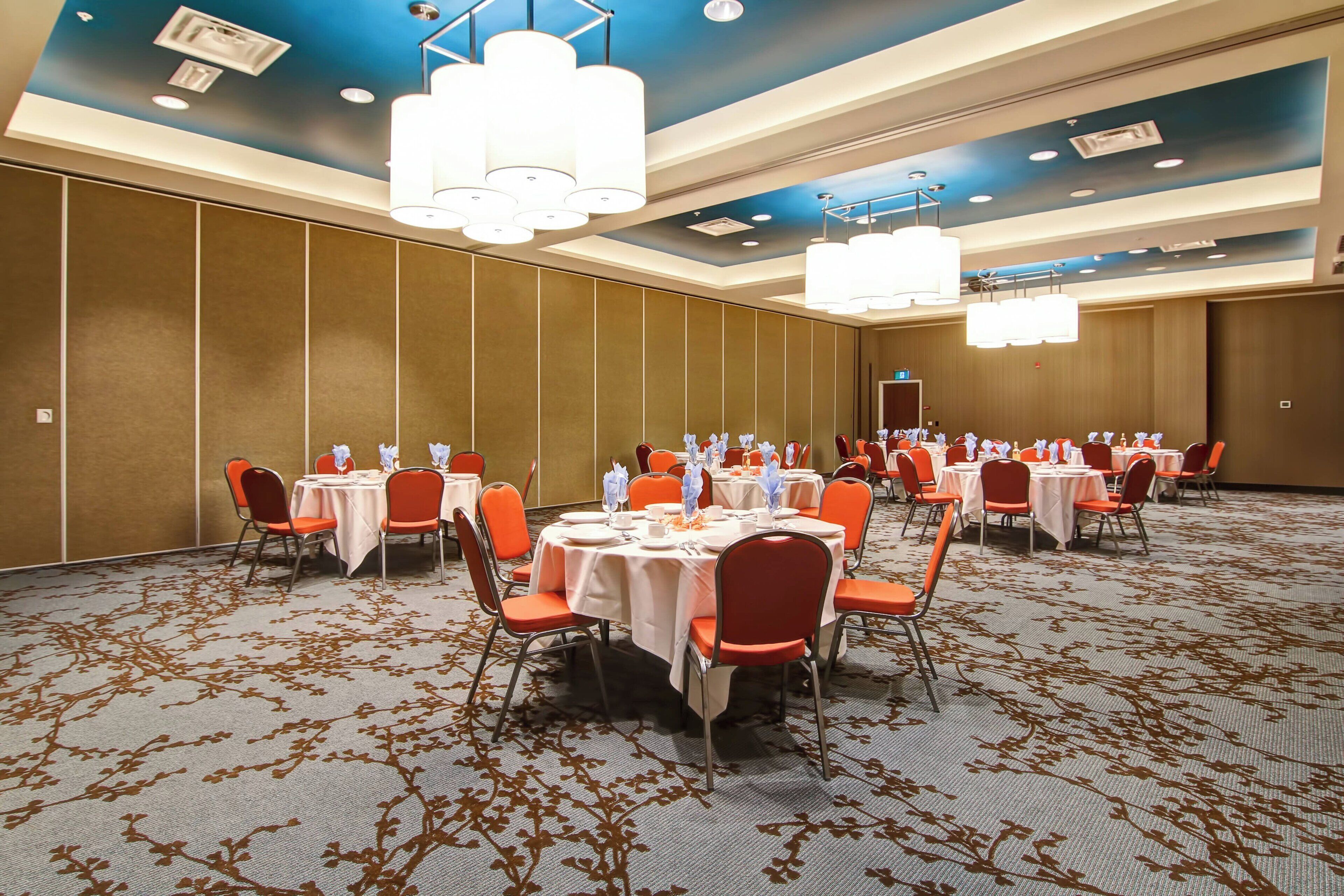 A conference room with round tables, orange chairs, and a carpeted floor.