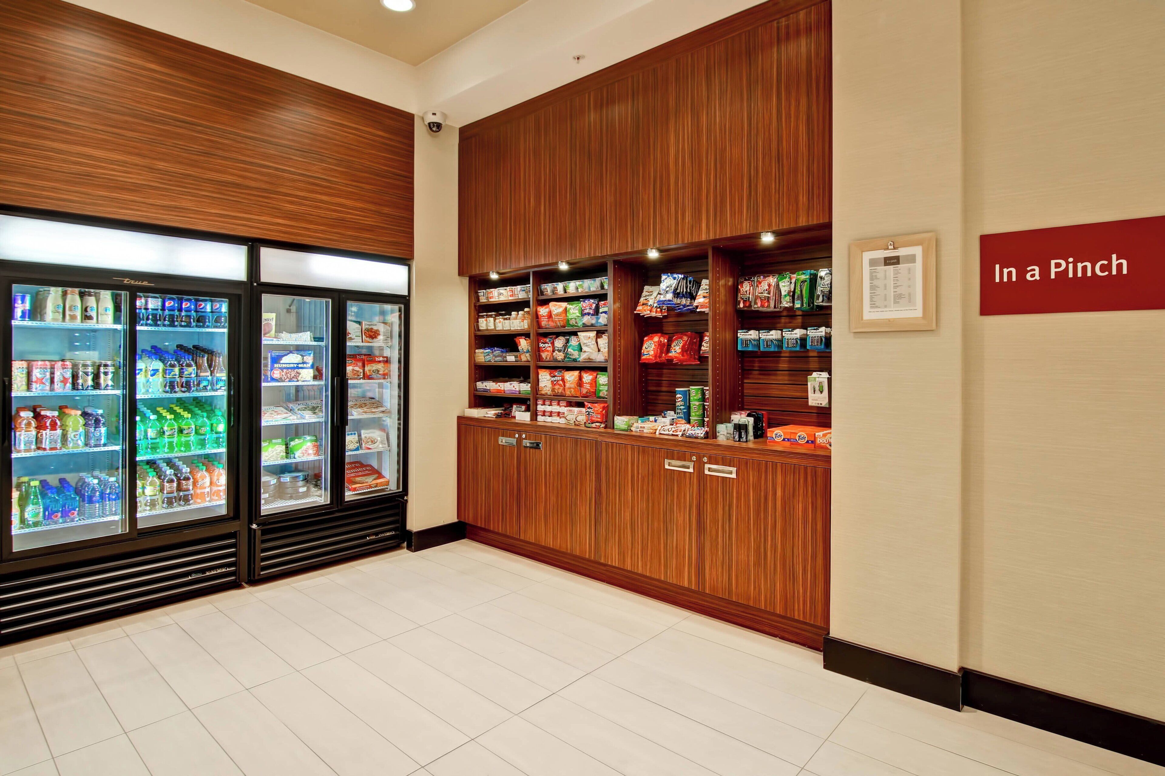A well-lit snack bar with refrigerated drinks and a variety of packaged snacks.