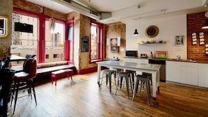 A modern kitchen with a bar area, wooden flooring, and red accents. - Hostel Fish (Denver)
