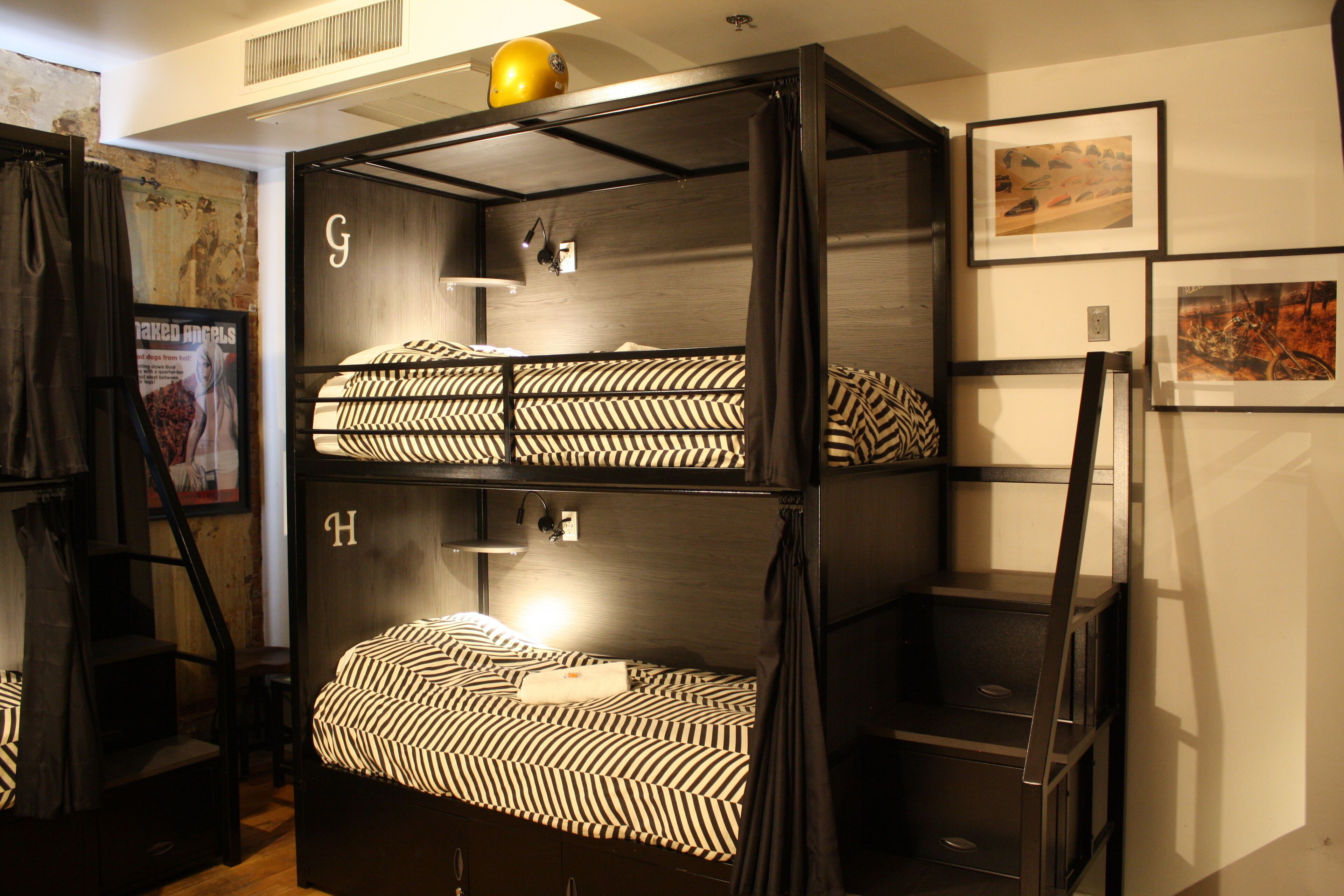 A bunk bed room with a ladder, a headboard with a letter, and a poster on the wall.