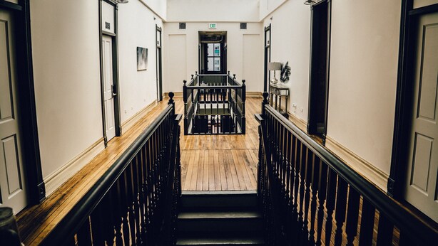 A grand staircase with a wooden finish and black balustrade, leading to an upper floor. - Hostel Fish (Denver)