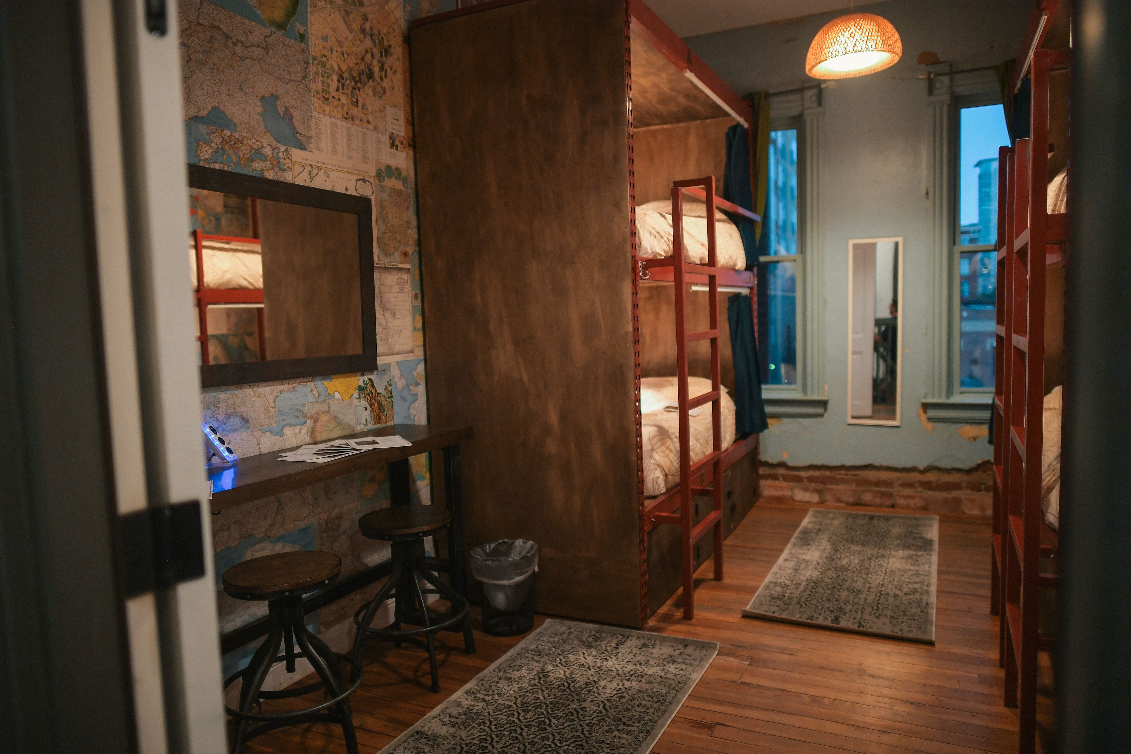 A cozy room with a bunk bed, a desk with a chair, a map on the wall, and a window with a view.
