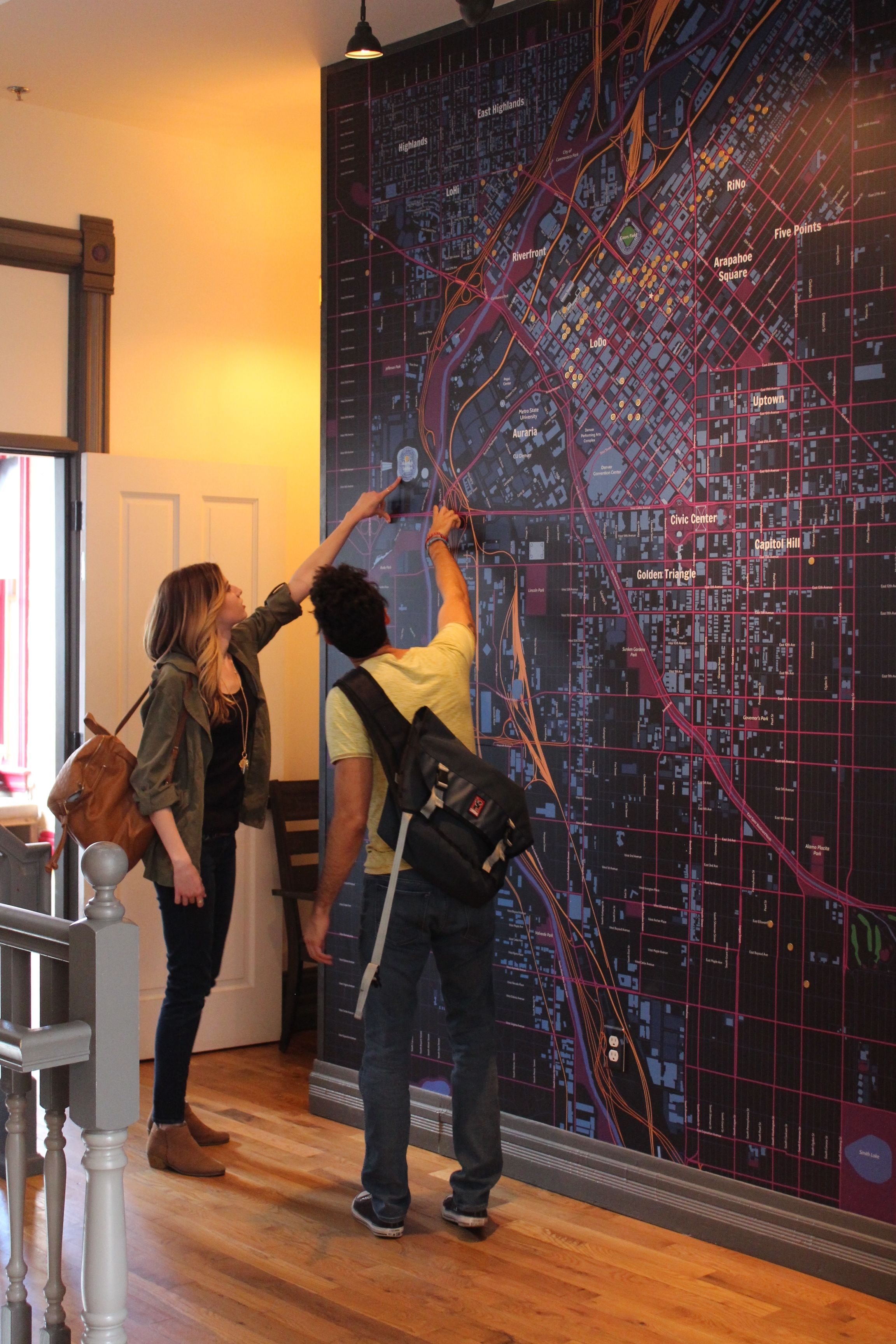 Una pareja revisa un mapa detallado de la ciudad colgado en una pared.