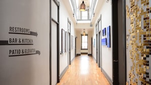 A hotel corridor with directional signs to restrooms, bar & kitchen, and patio & elevator. - Hostel Fish (Denver)