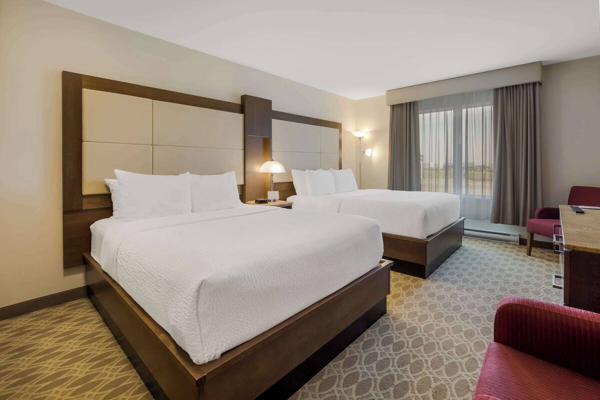 Habitación de hotel con dos camas, un escritorio y una silla.