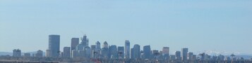 A city skyline with multiple high-rise buildings, some under construction, and a clear sky.