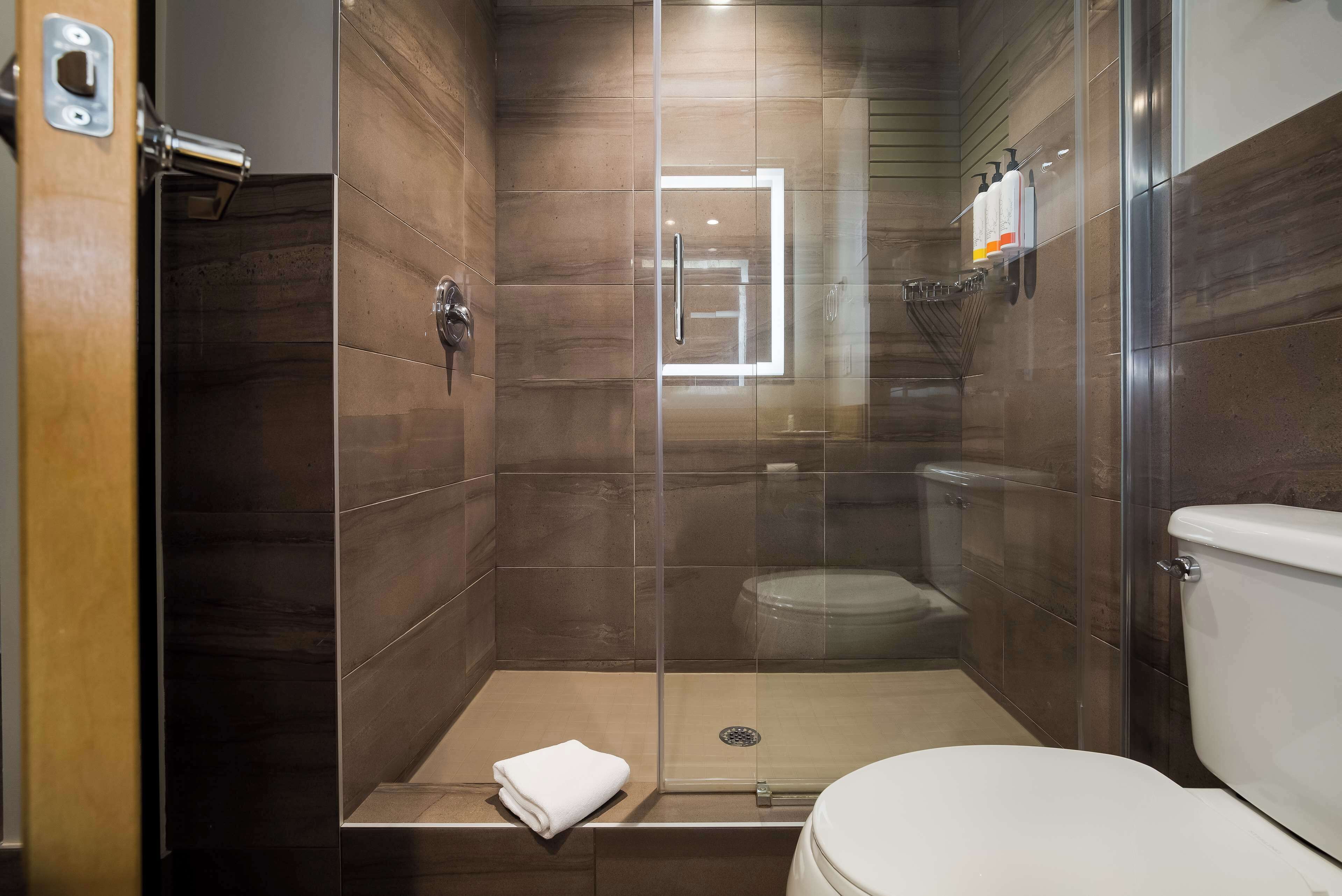 Un baño moderno con ducha de vidrio, inodoro y perchero para toallas.